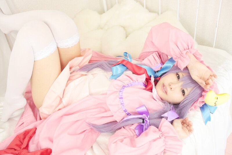 cosplayer in pink dress lying on bed