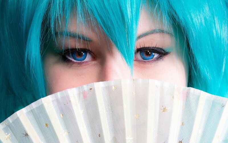 cosplayer with blue hair and fan