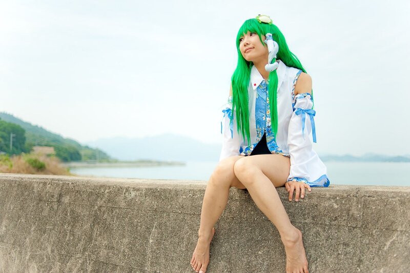 cosplayer with green hair sitting by water