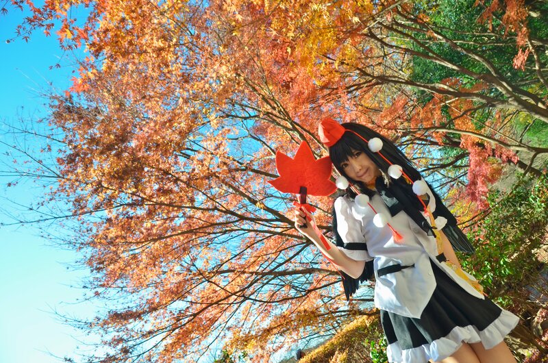 cosplayer with maple leaf in autumn