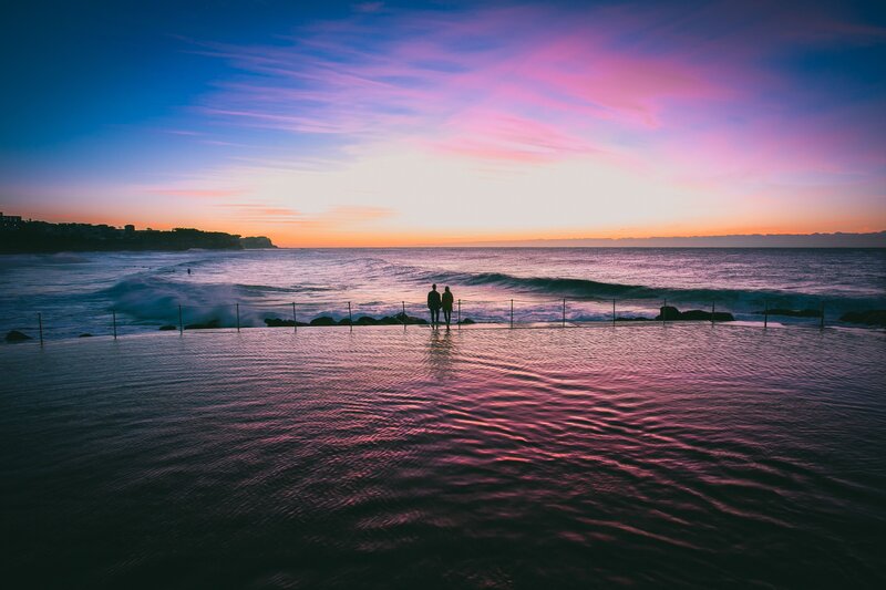 Couple at ocean pool sunset