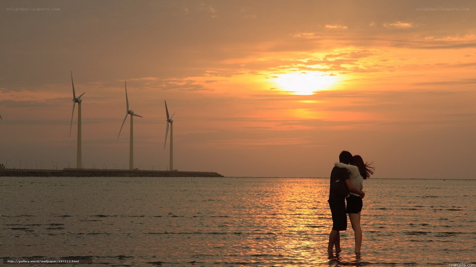 Couple at sunset by wind turbines