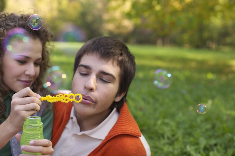 Couple blowing bubbles in park