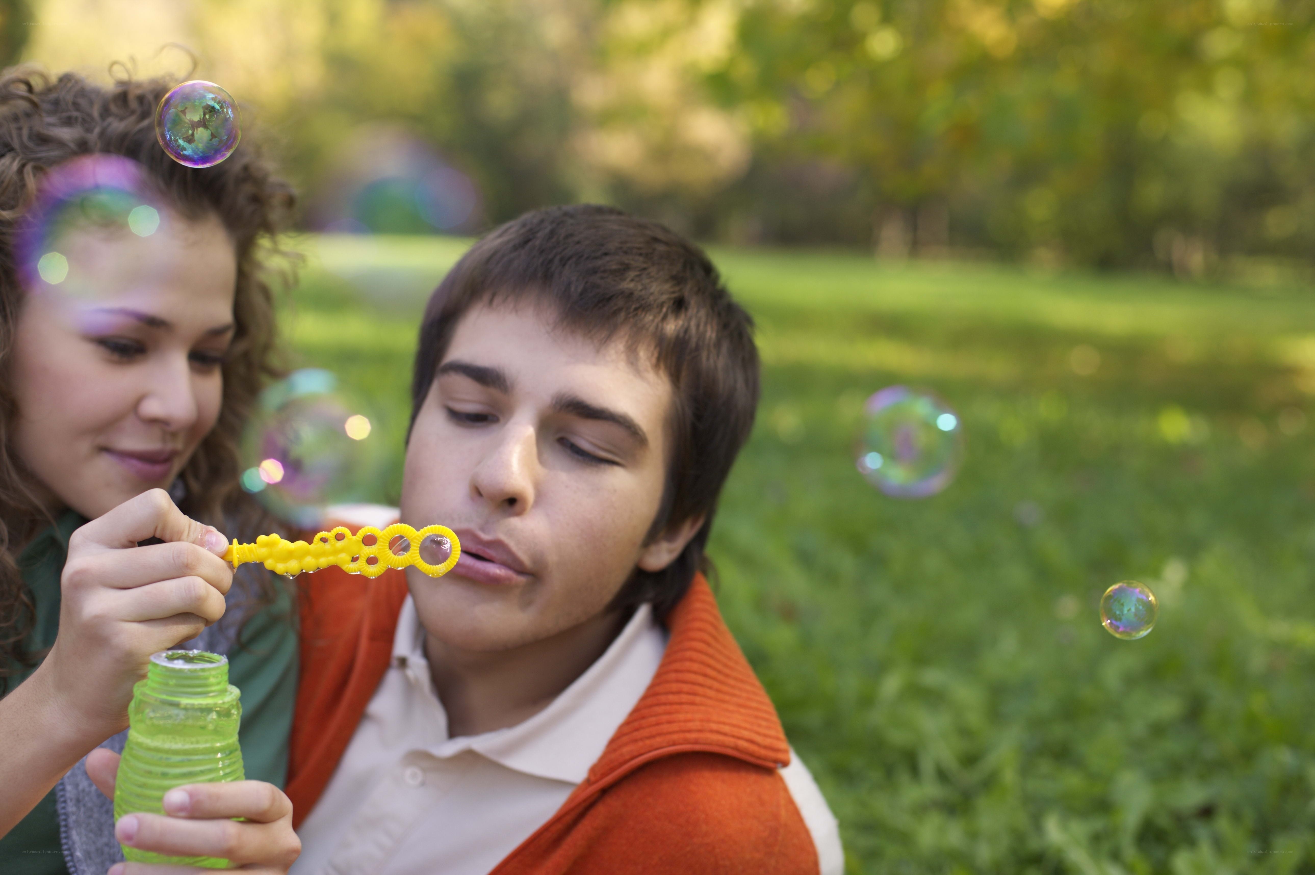 Couple blowing bubbles in park