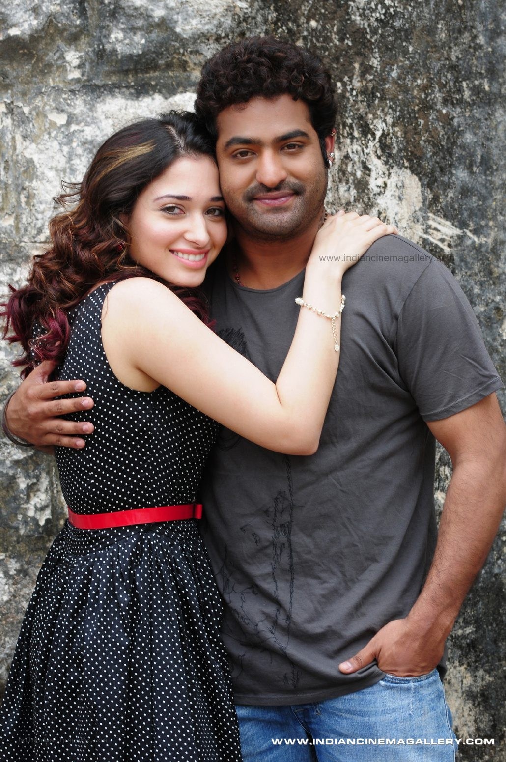 couple embracing against stone wall