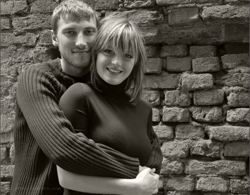 couple embracing by brick wall