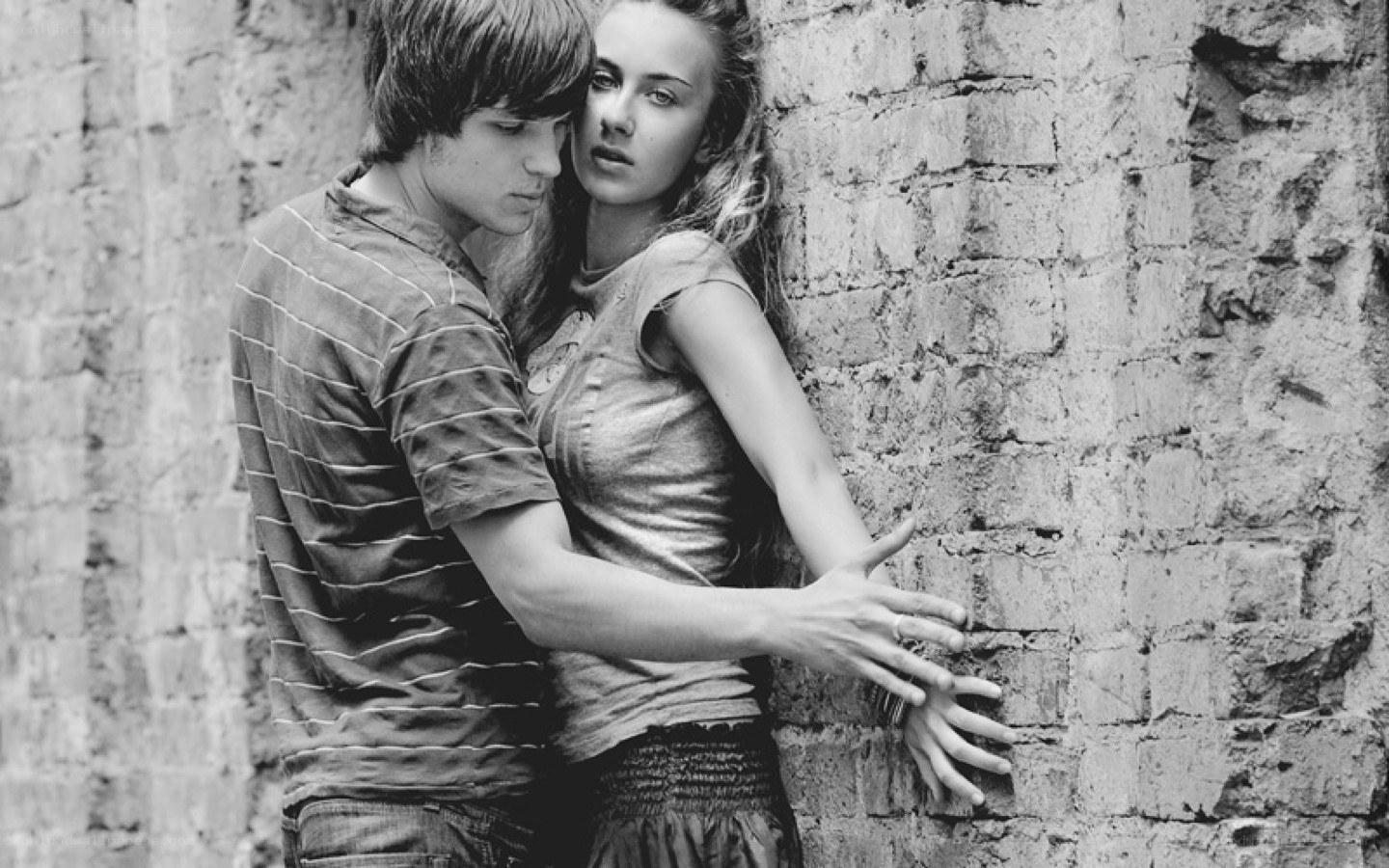 couple embracing by brick wall