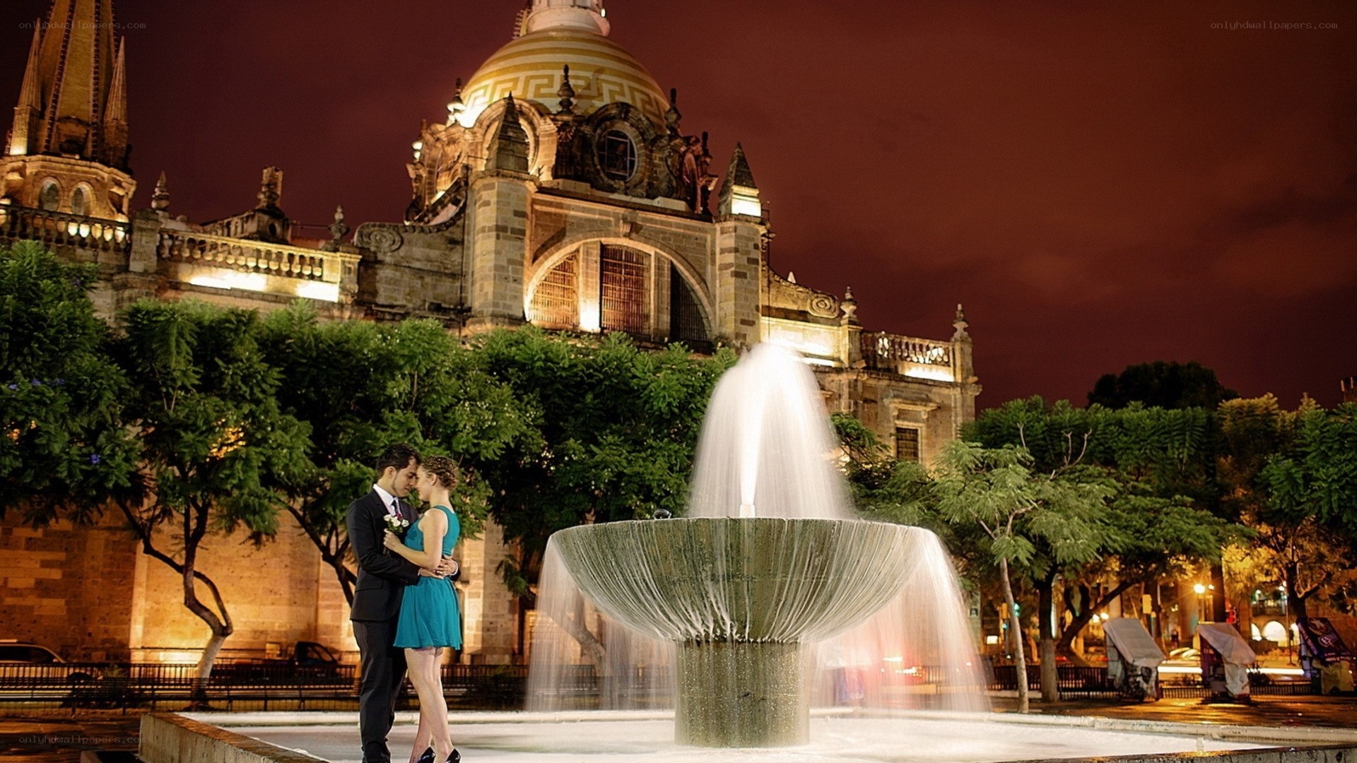 Couple embracing by fountain at night