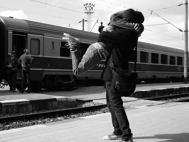 Couple Hugging at Train Station — Black, Dramatic, Afternoon