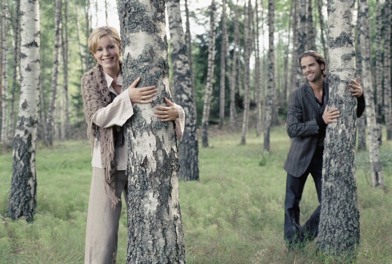 Couple hugging trees in forest