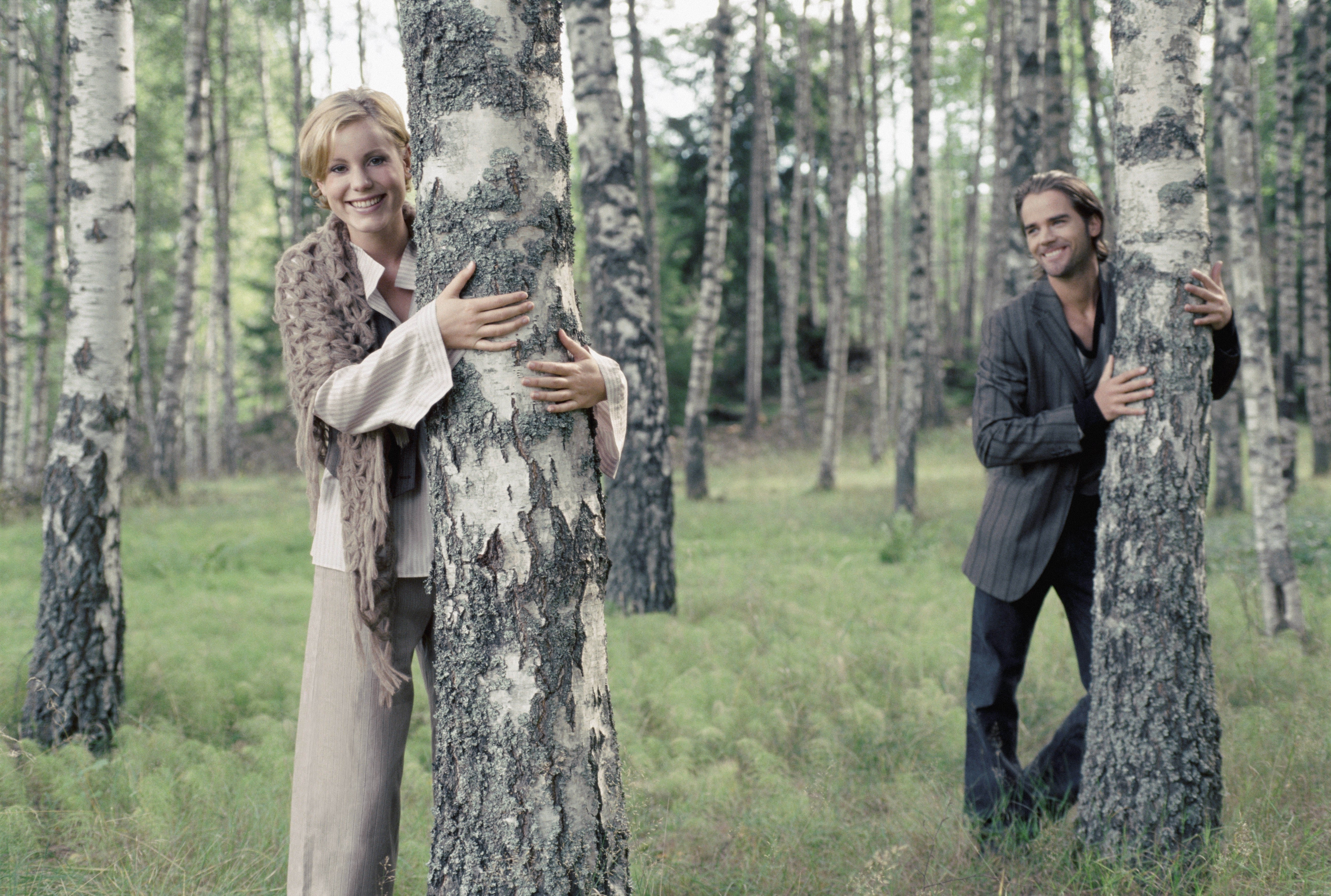 Couple hugging trees in forest