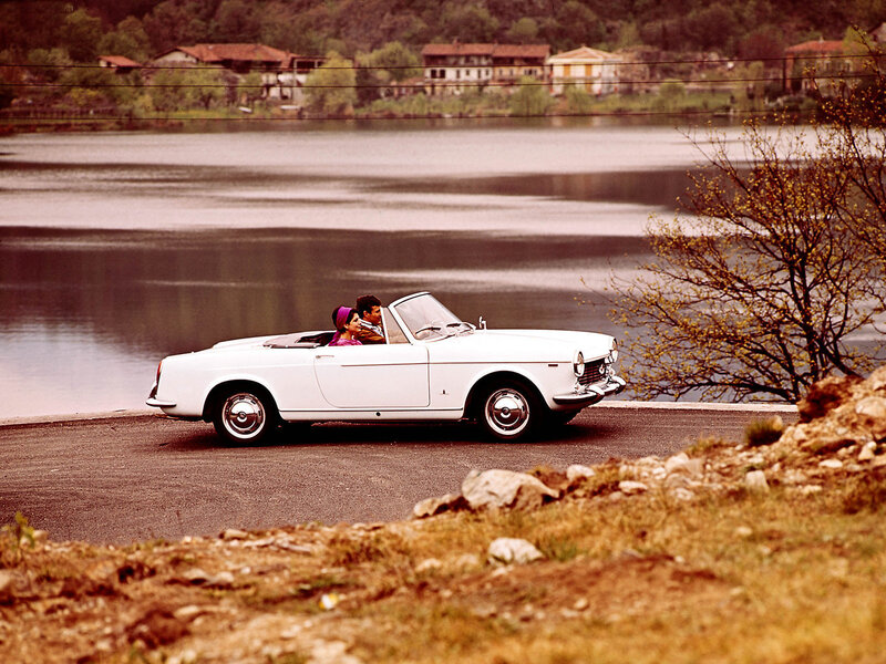 Couple in white convertible by lake