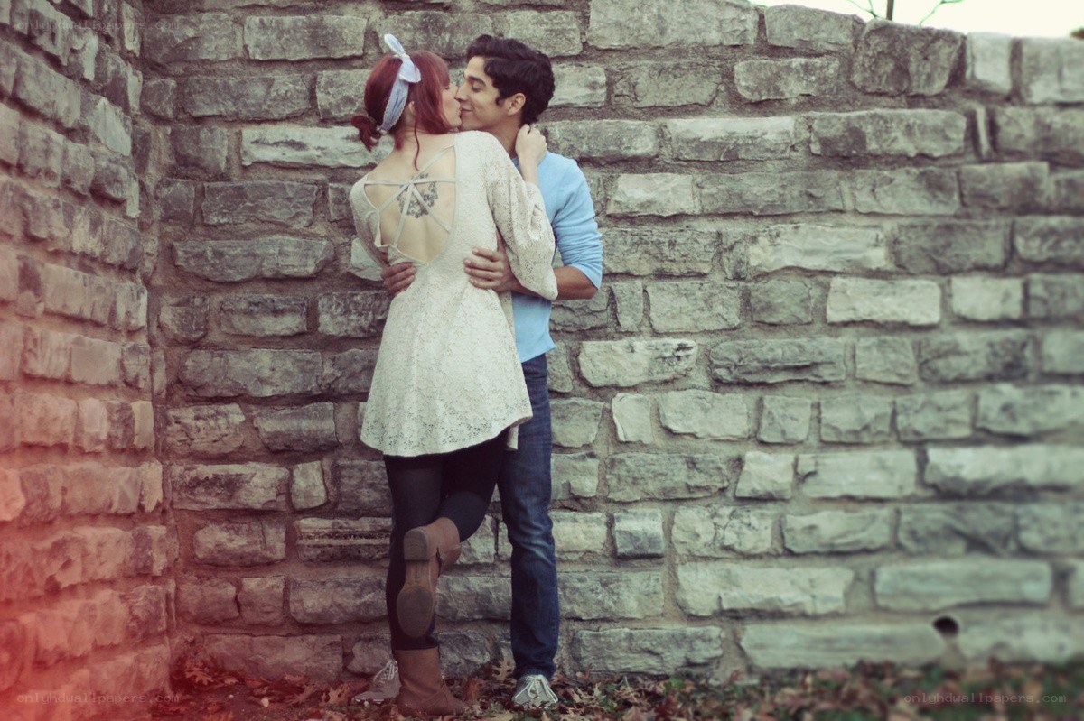 couple kissing by stone wall