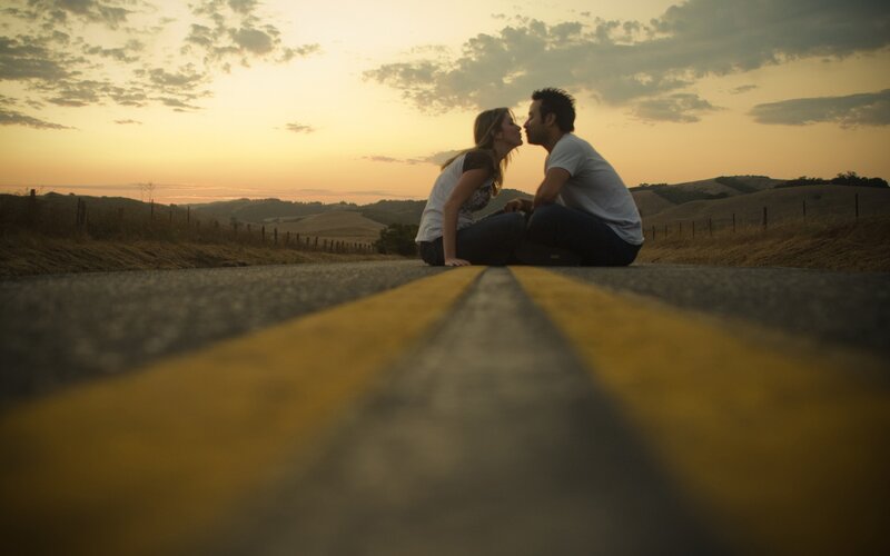 Couple kissing on a road at sunset