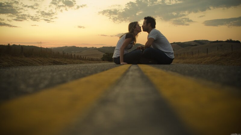 Couple kissing on a road at sunset