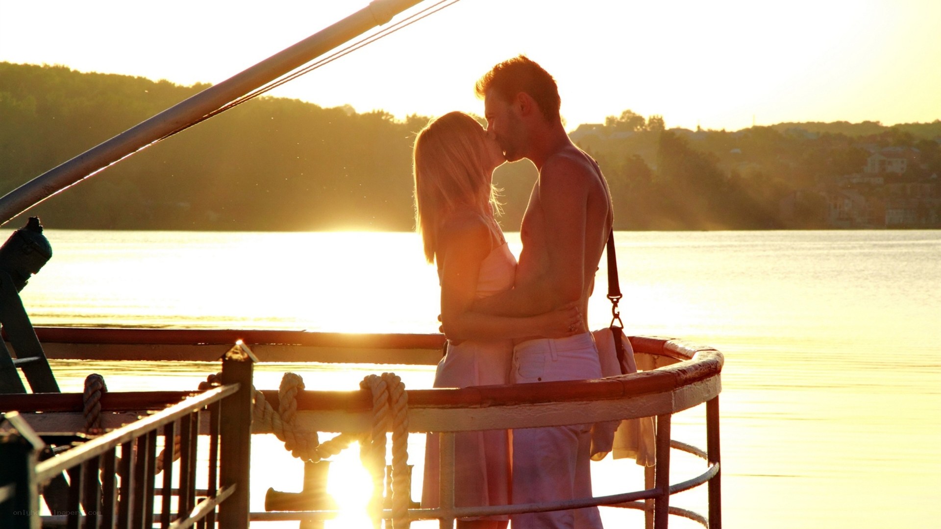 Couple kissing on boat at sunset