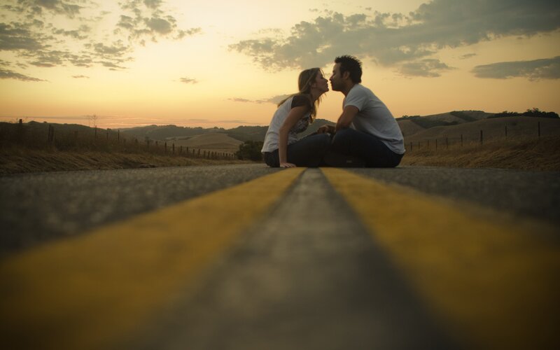 Couple kissing on road at sunset