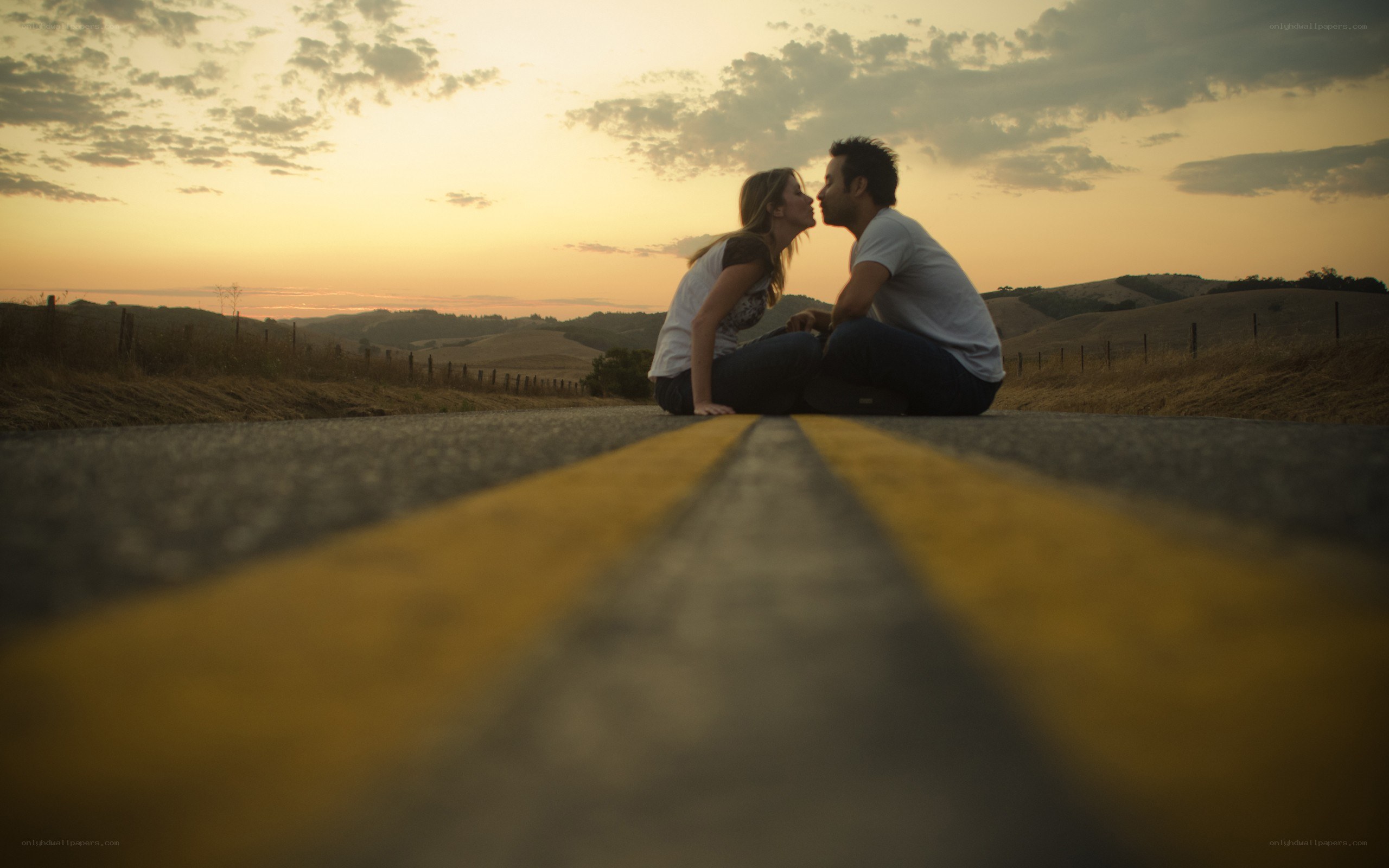 Couple kissing on road at sunset