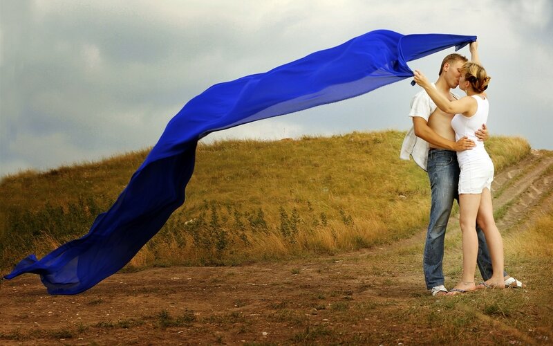 Couple kissing under blue cloth