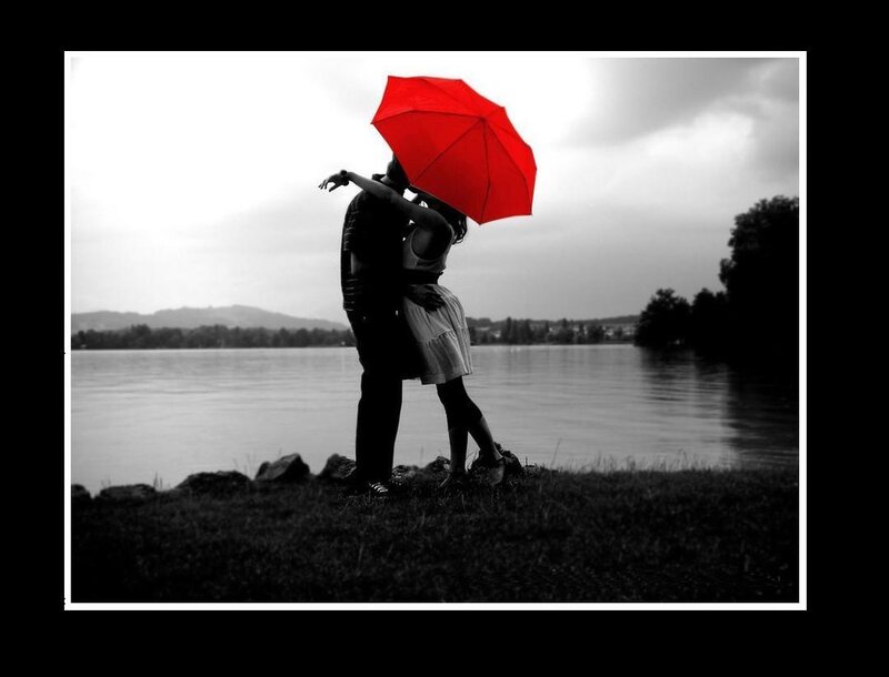 Couple kissing under red umbrella