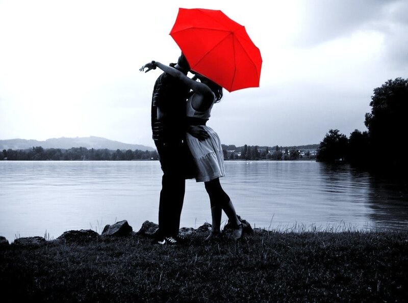 Couple kissing under red umbrella