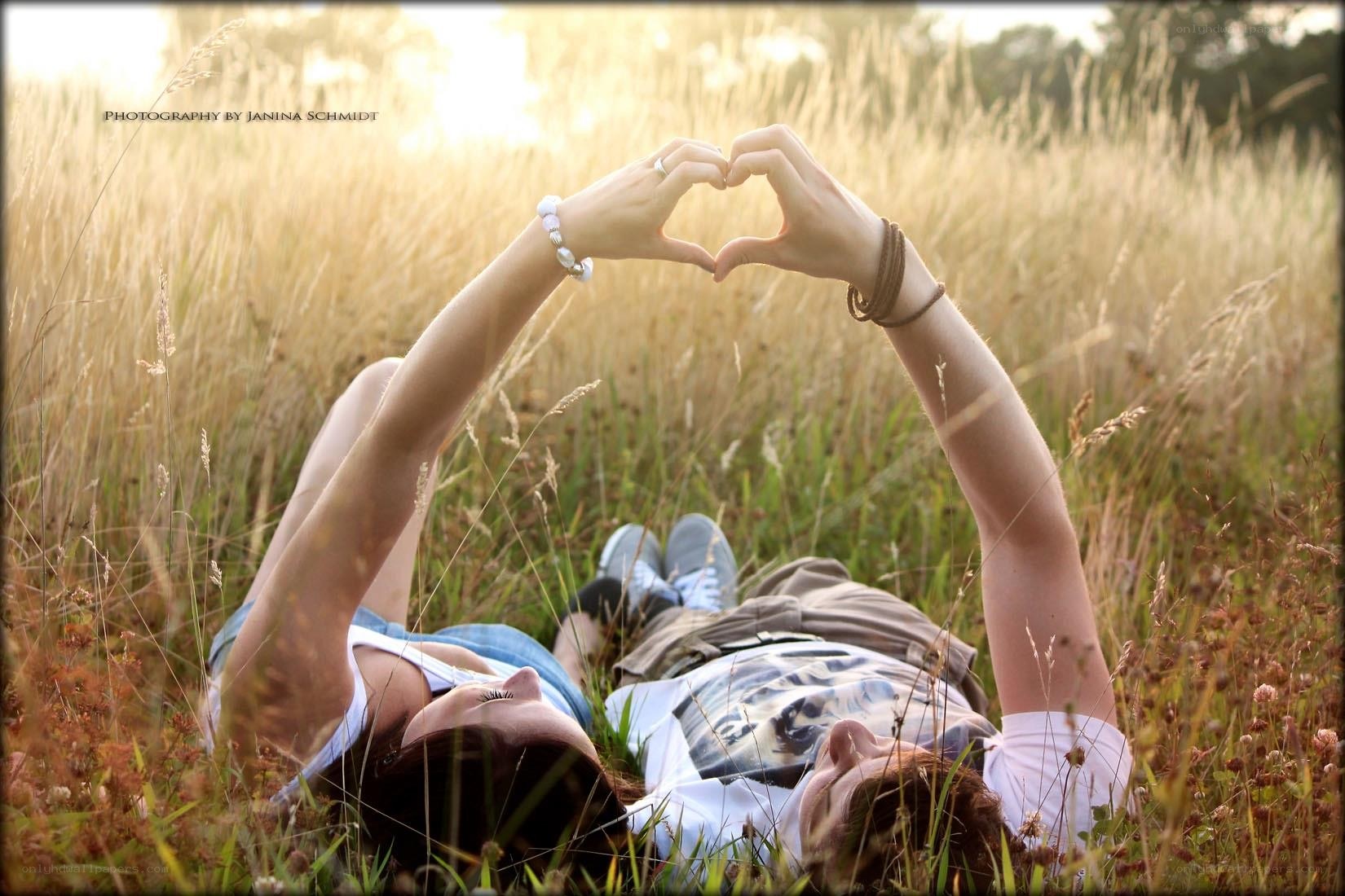 Couple making heart shape in field