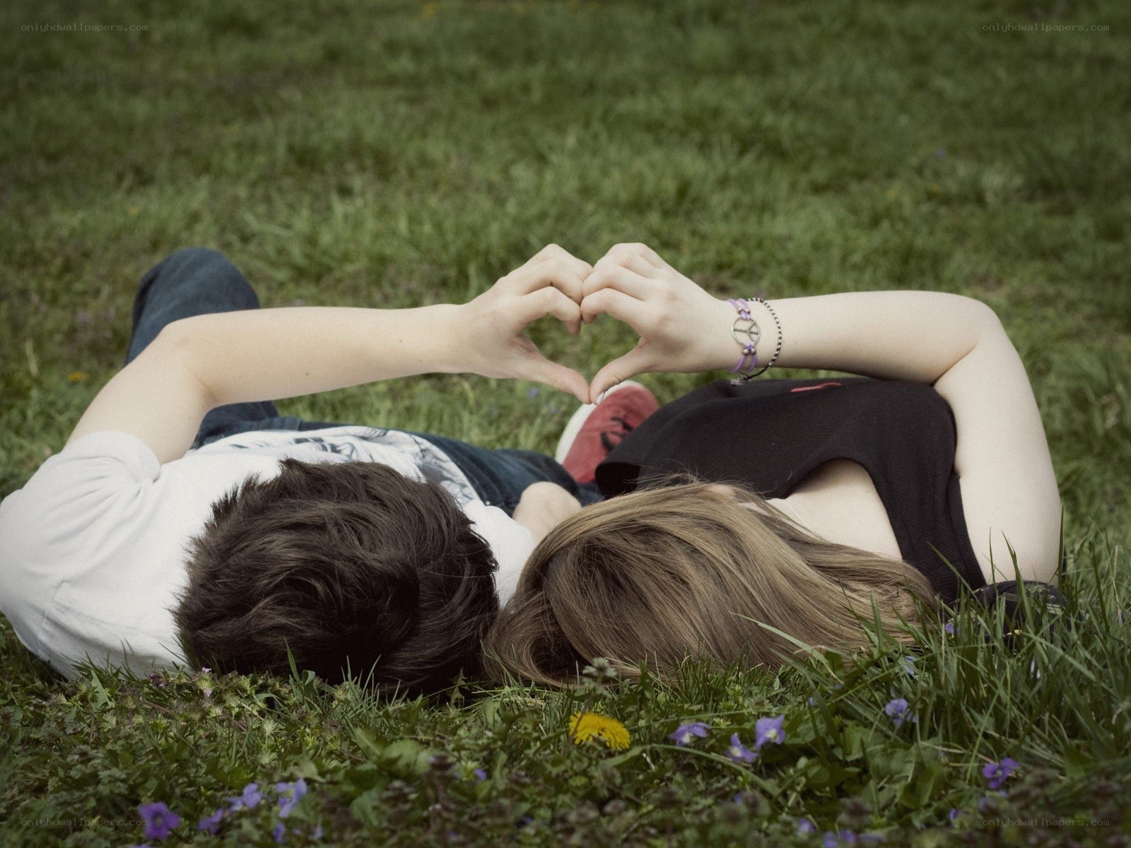 Couple making heart shape on grass