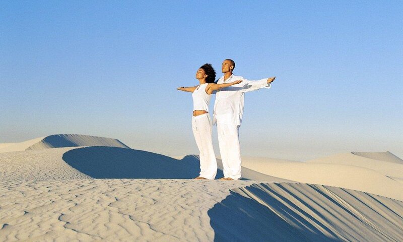 Couple meditating on sand dunes