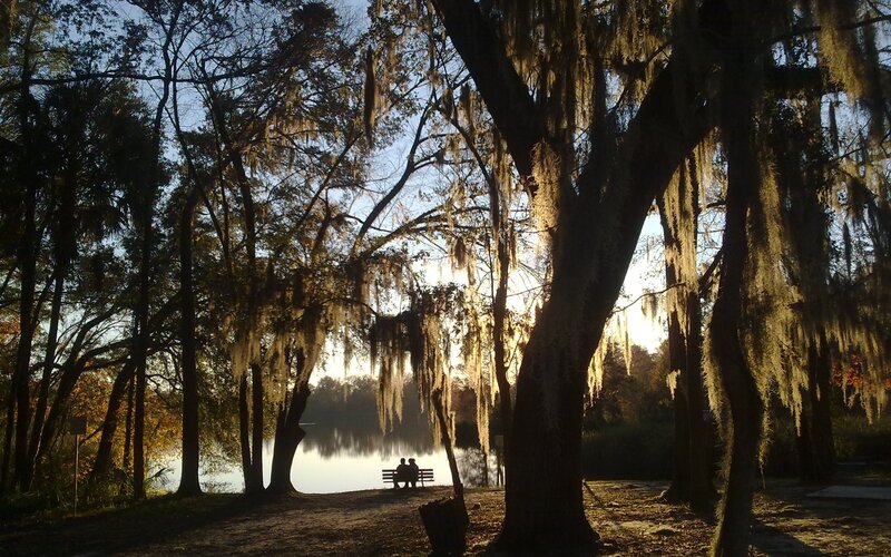 Couple on bench by lake at sunset