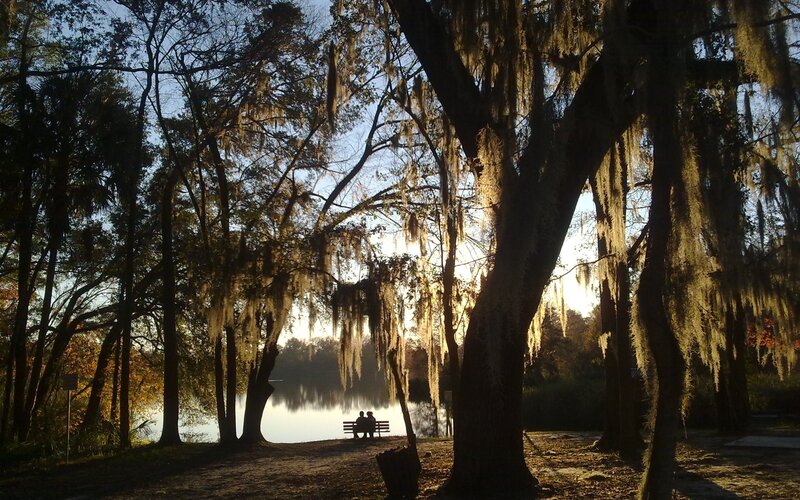 Couple on bench by lake at sunset