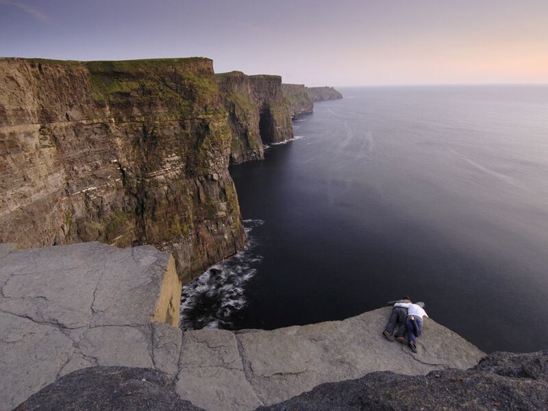 Couple on cliff edge at sunset