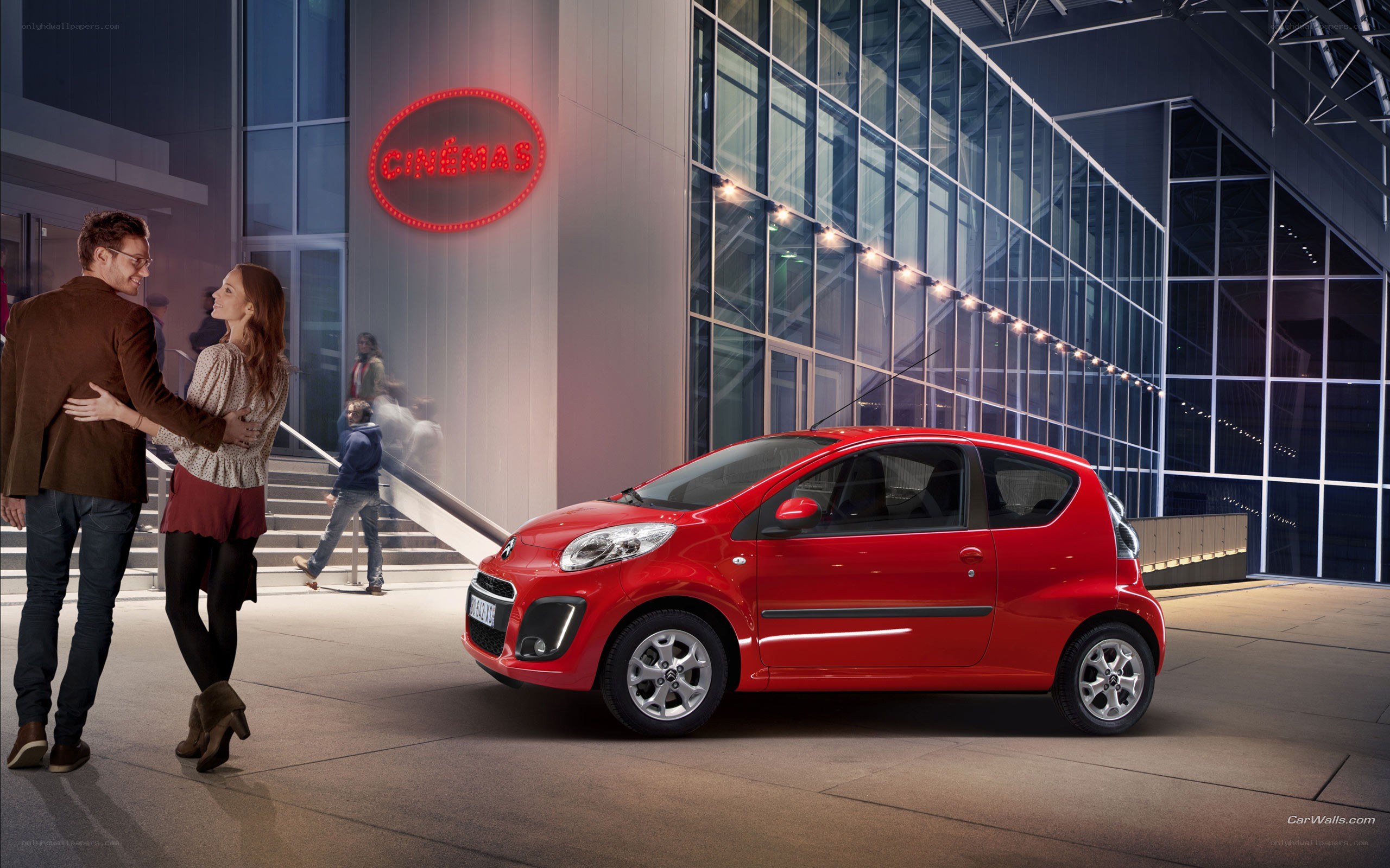 Couple outside cinema with red car