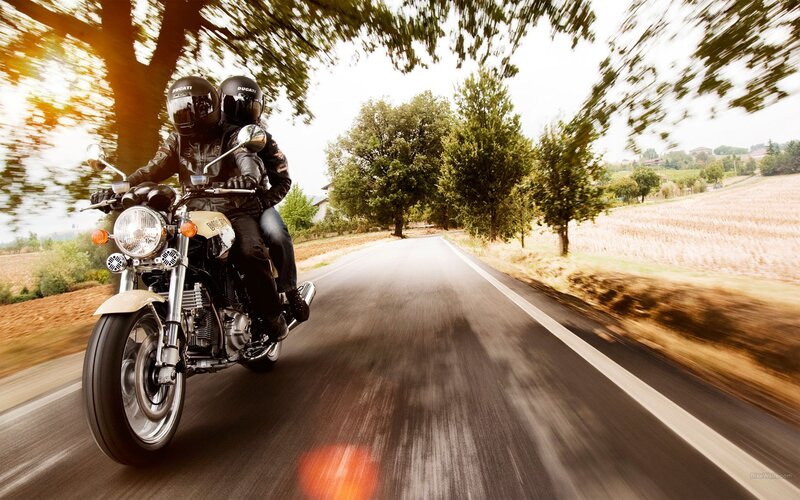 Couple riding motorcycle on country road