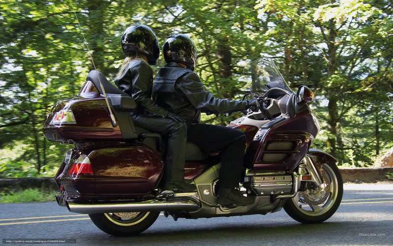 Couple riding motorcycle on forest road