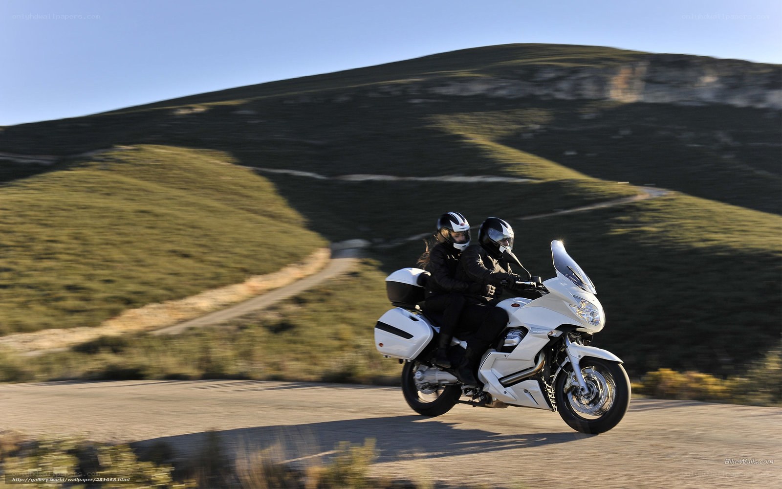 Couple riding motorcycle on hill road
