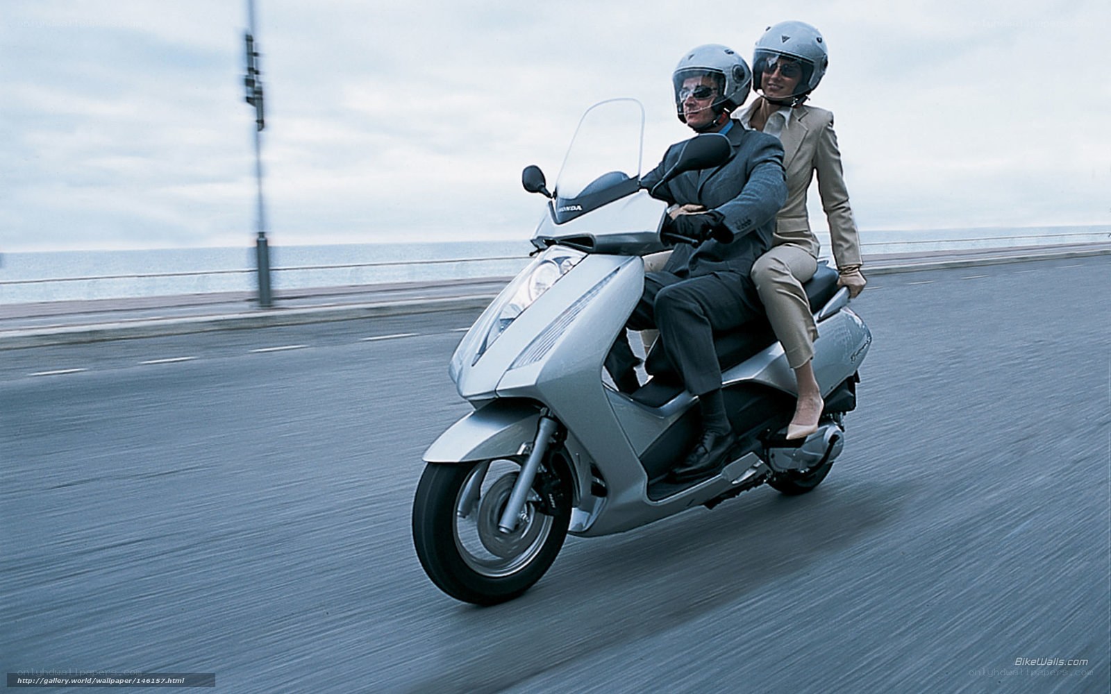 Couple riding scooter on coastal road