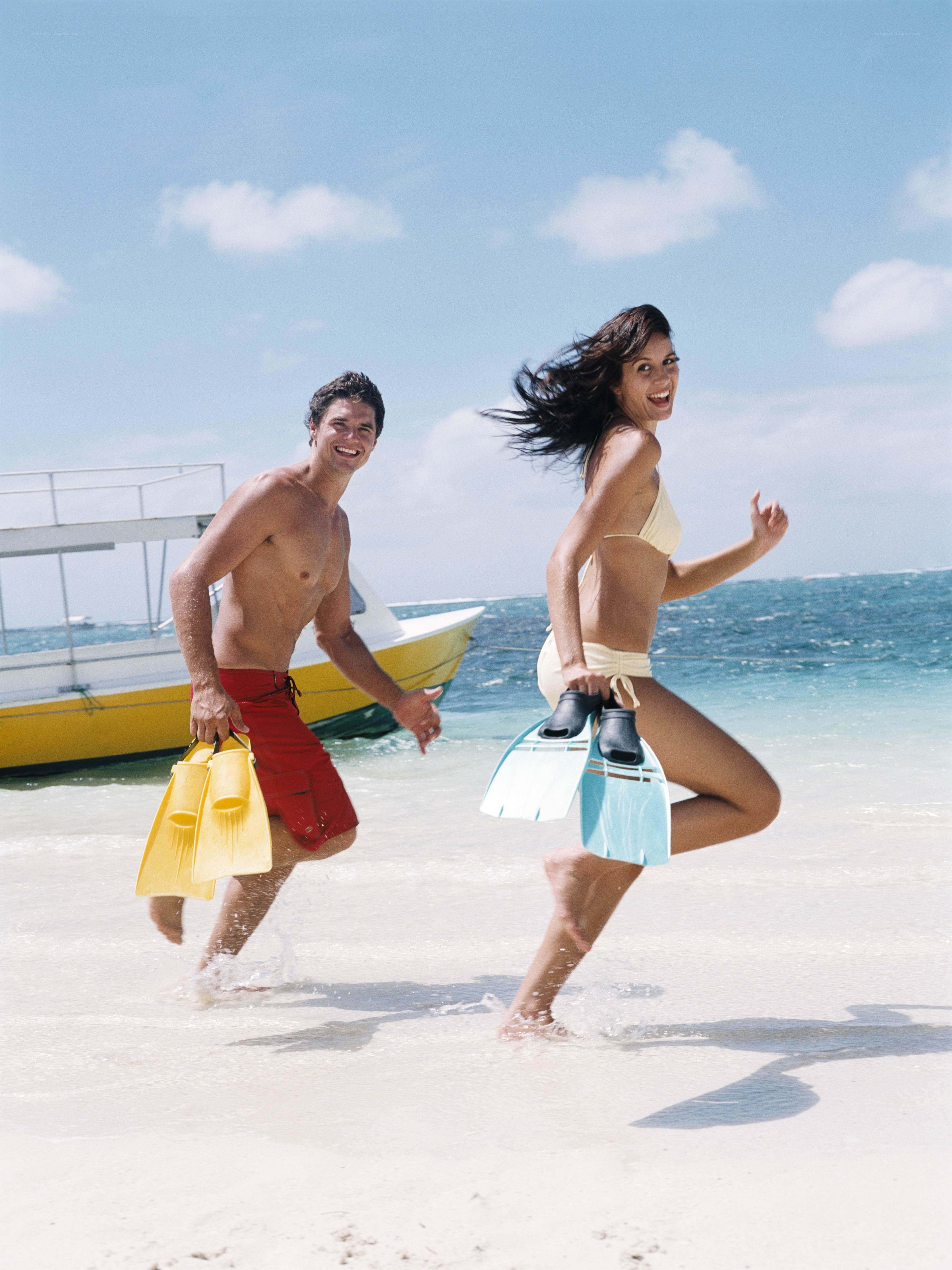 Couple running on beach with flippers