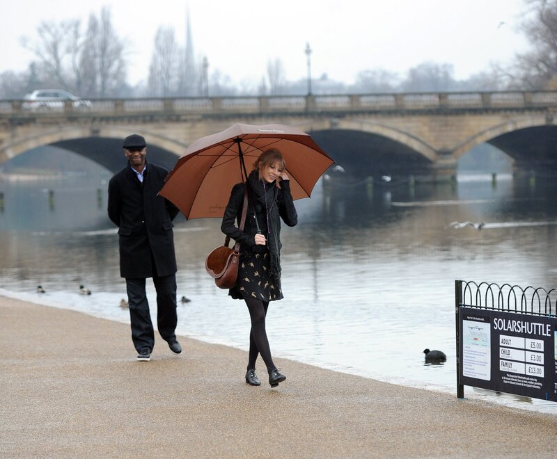 Couple walking by river with umbrella