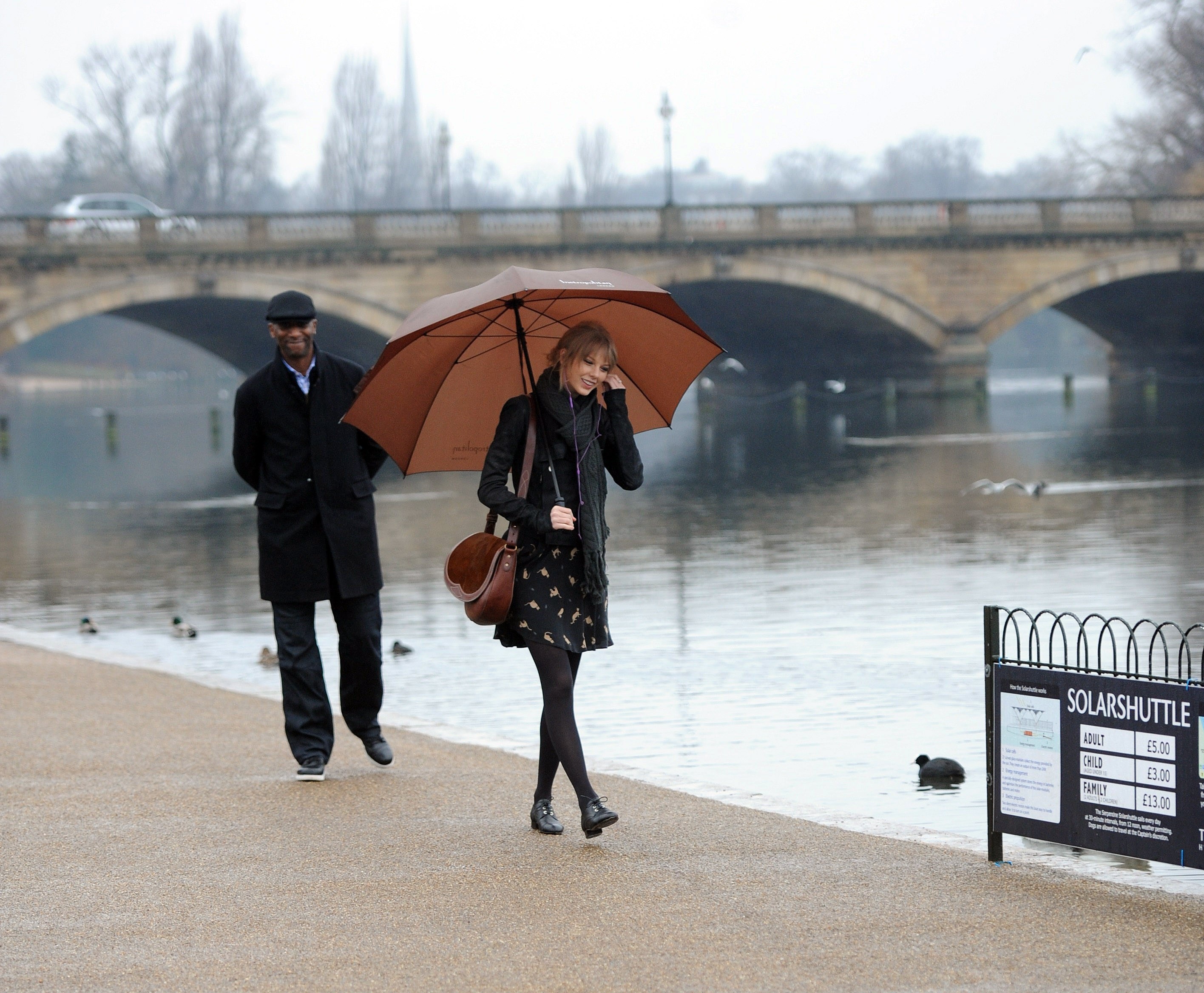 Couple walking by river with umbrella