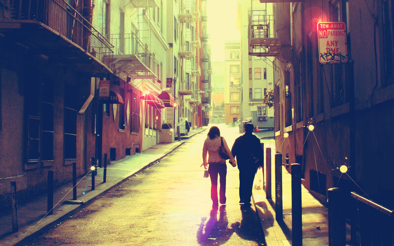 Couple walking down alley at sunset