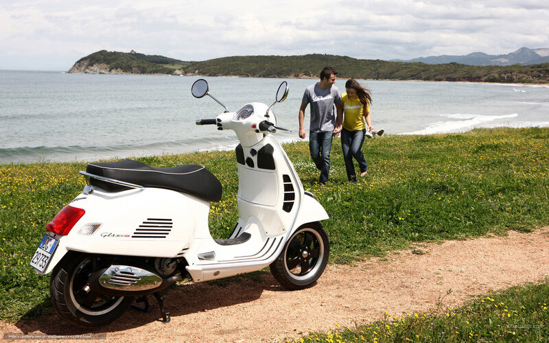 Couple walking near scooter by sea