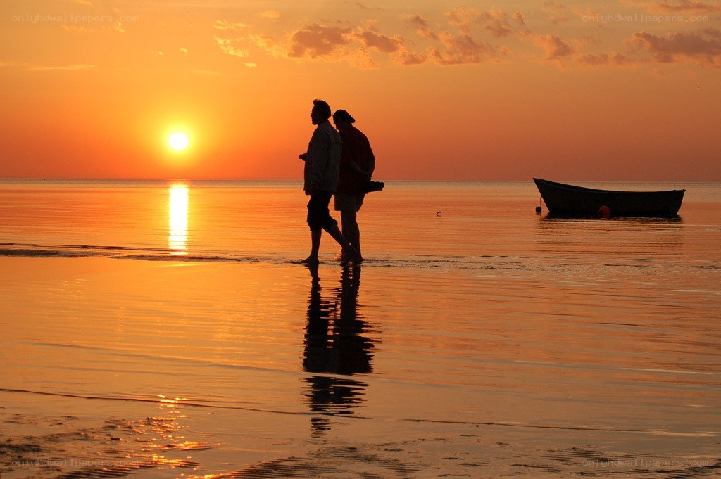 Couple walking on beach at sunset