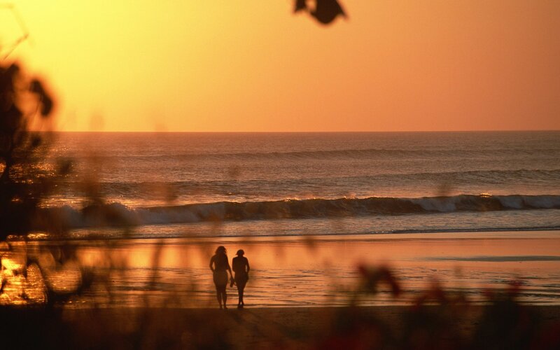 Couple walking on beach at sunset