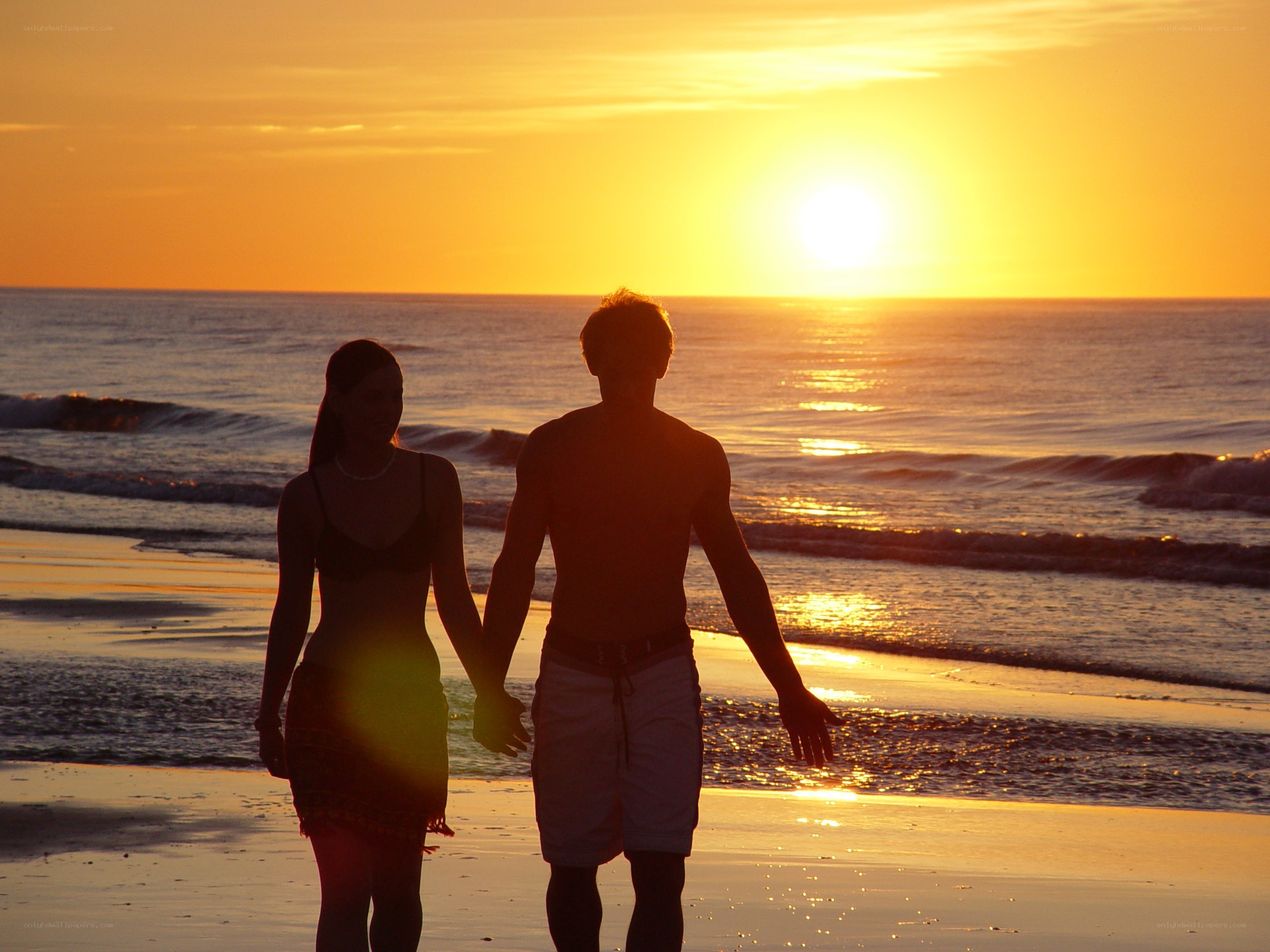 Couple walking on beach at sunset