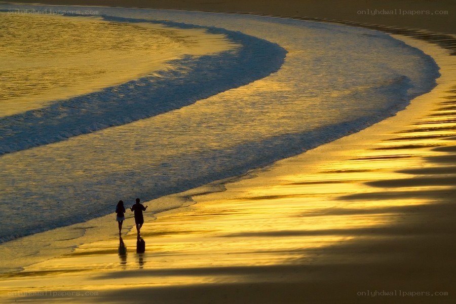 Couple walking on beach at sunset