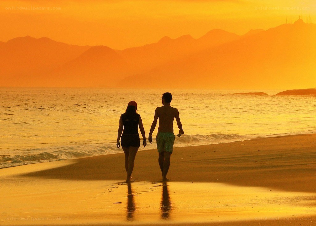 Couple walking on beach at sunset