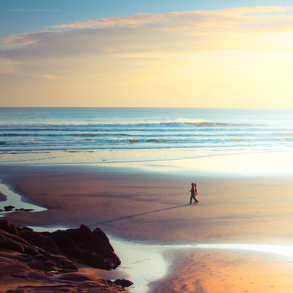 Couple walking on beach at sunset
