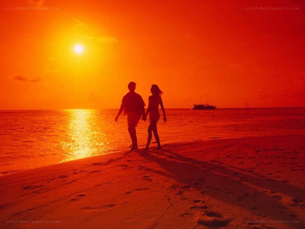 Couple walking on beach at sunset