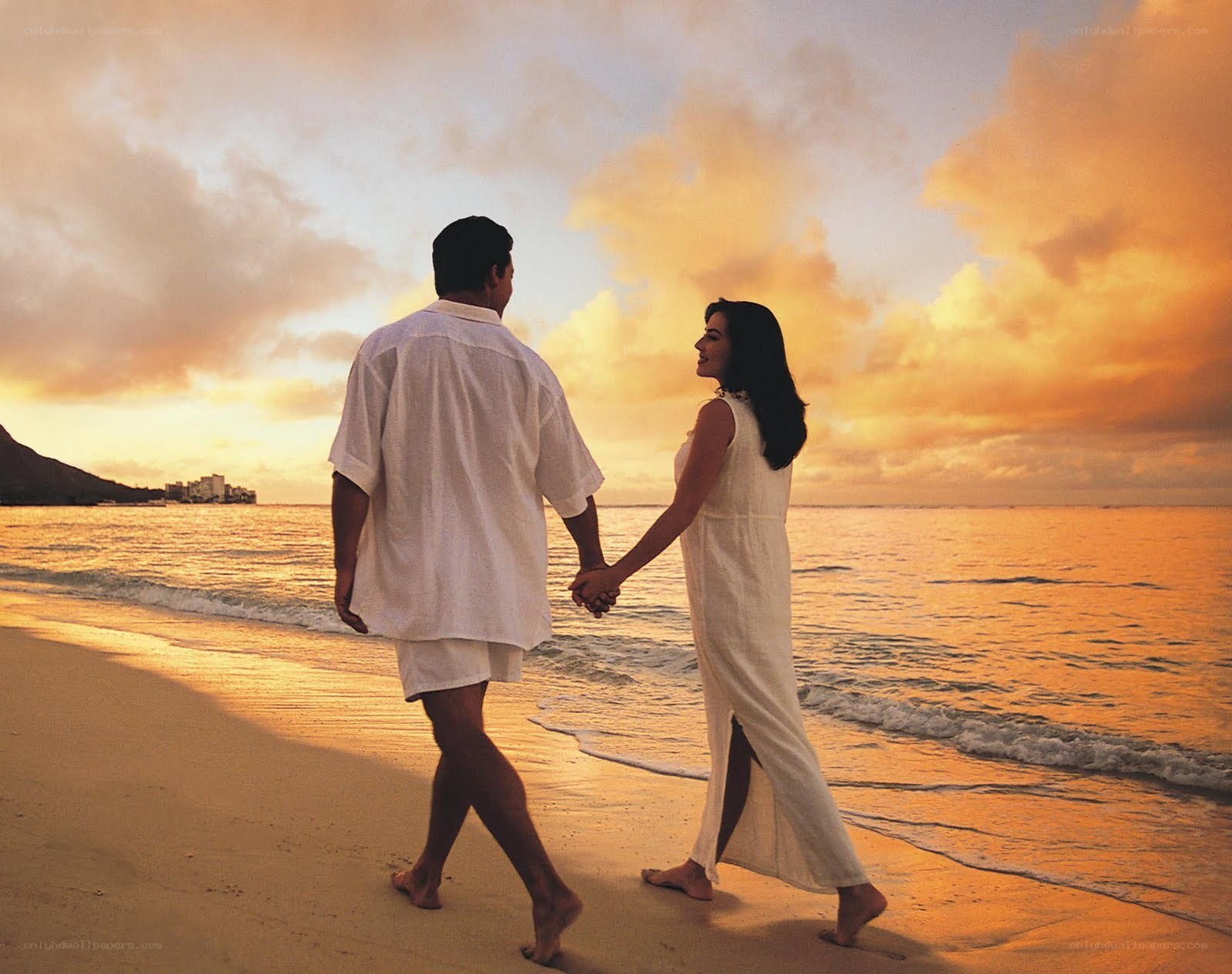 Couple walking on beach at sunset