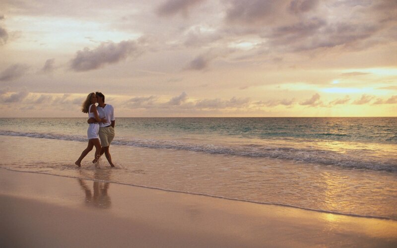 Couple walking on beach at sunset